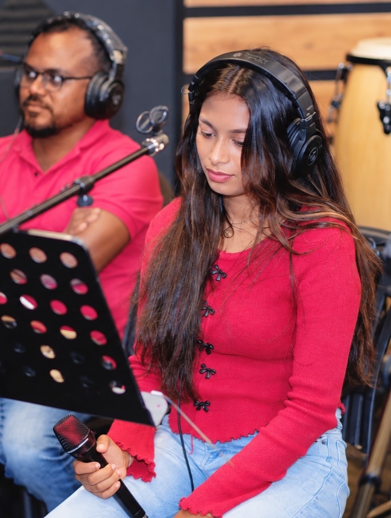 Kawya Erandi in the studio holding a microphone between takes
